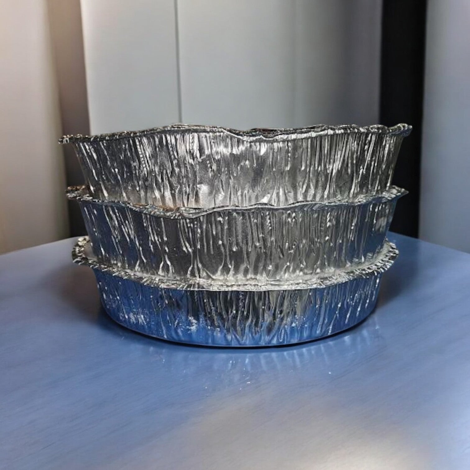 Three stacked Pequod’s Deep Dish Pizza containers, part of the 3-Pack Combo featuring Cheese, Pepperoni & Sausage varieties with free shipping, rest on a blue surface against a neutral background.