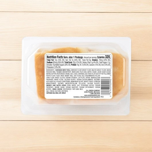 A pack of E.A. Sween's Smoked Ham and Swiss Sliders, with a 30-day shelf life once thawed, elegantly rests on a wooden surface, showcasing its nutrition facts label.