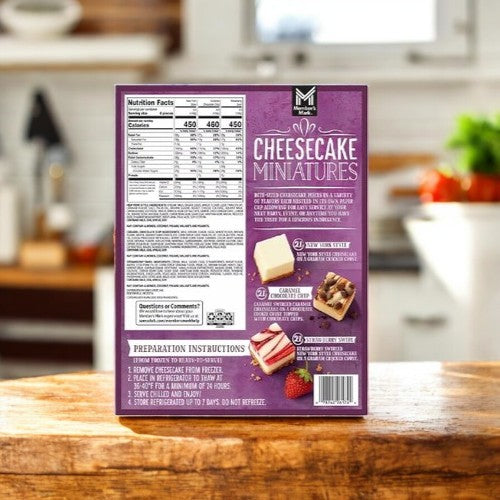 The back of a Member's Mark Cheesecake Minis Variety Pack – 3 Pack box is shown on a kitchen counter, featuring nutrition facts, preparation steps, and images of tasty bite-sized cheesecakes.