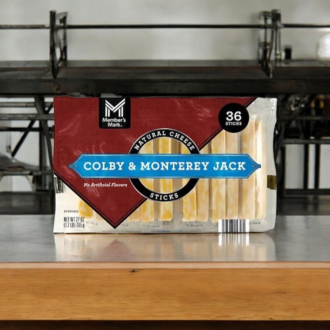 A 36-count pack of Member's Mark Colby and Monterey Jack Cheese Sticks, free from artificial flavors and crafted with quality ingredients, is shown on a wooden counter. Ideal as a wholesome snack.