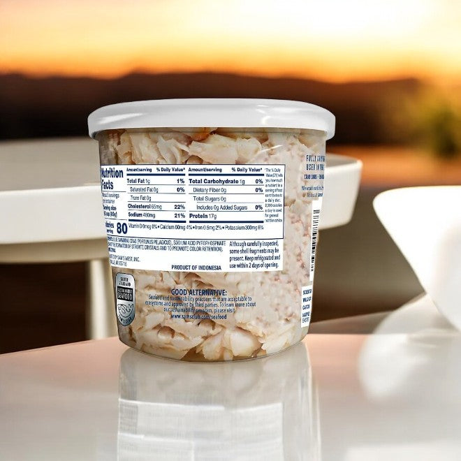 A plastic container of sustainably sourced sliced almonds rests on a table, illuminated by sunrise—ideal for pairing with Member's Mark Wild Caught Premium Lump Crab Meat as seafood lovers relish the morning.