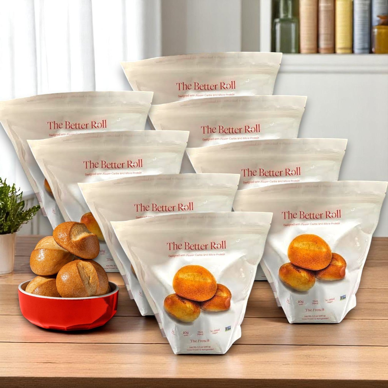 Eight bags of BetterBrand's The Better Roll – French Style (64 rolls total) are arranged on a table, with a red bowl of French rolls in front—ideal for anyone searching for a healthier bread option. In stock and ready to ship!.