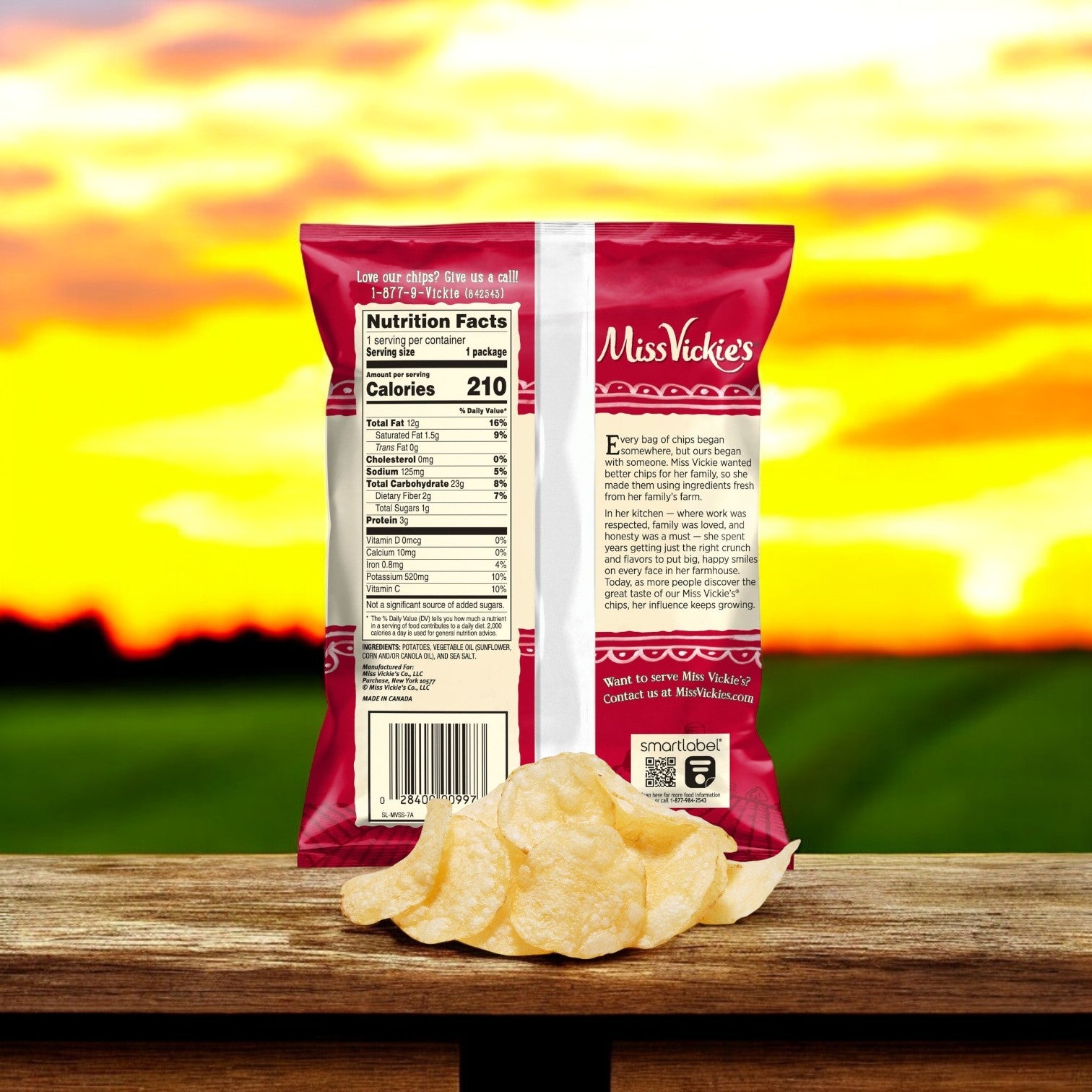 A bag of Miss Vickie’s Chip Potato Regular Sea Salt 64/1.375 oz. by Miss Vickie's is shown from the back with visible nutrition facts, placed on a wooden ledge with chips in front and a sunset in the background.