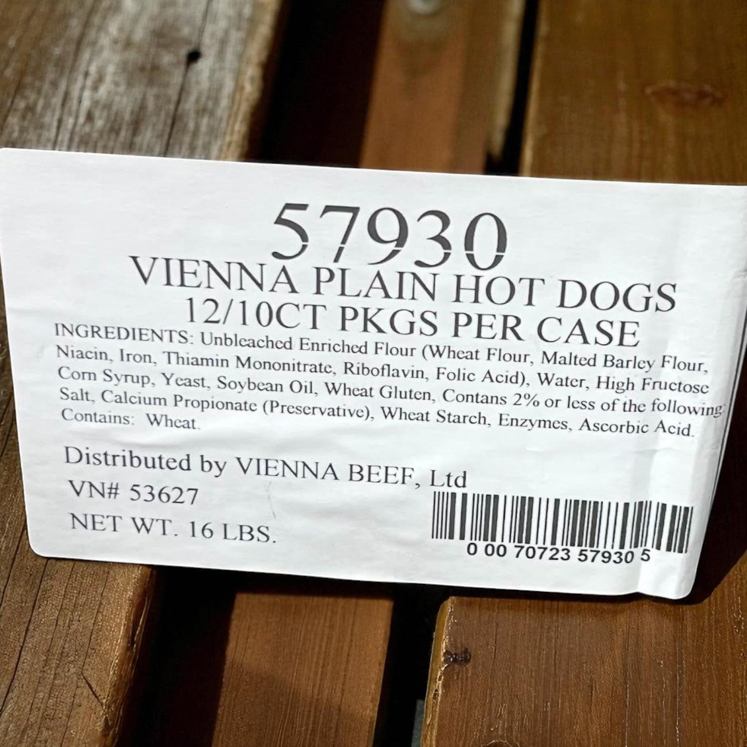 Label for Vienna Beef Plain Hot Dog Buns with product name, pack info (12 packs/10 buns, 120 per case), brand, ingredients, distributor details, and barcode—great alongside Vienna hot dogs—placed on a wooden surface.