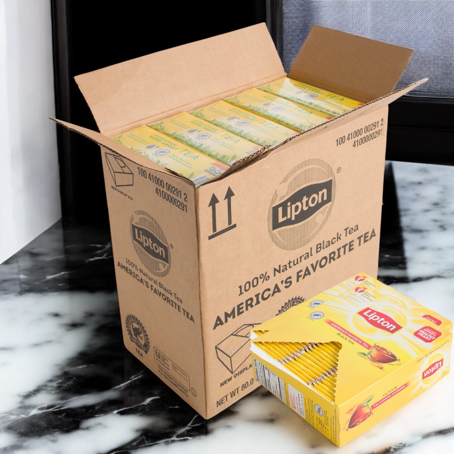 A box of Lipton Tea Hot Bag Black Envelope 10/100 CT by Lipton sits open on a marble table, with an individual box of wrapped tea bags placed beside it.