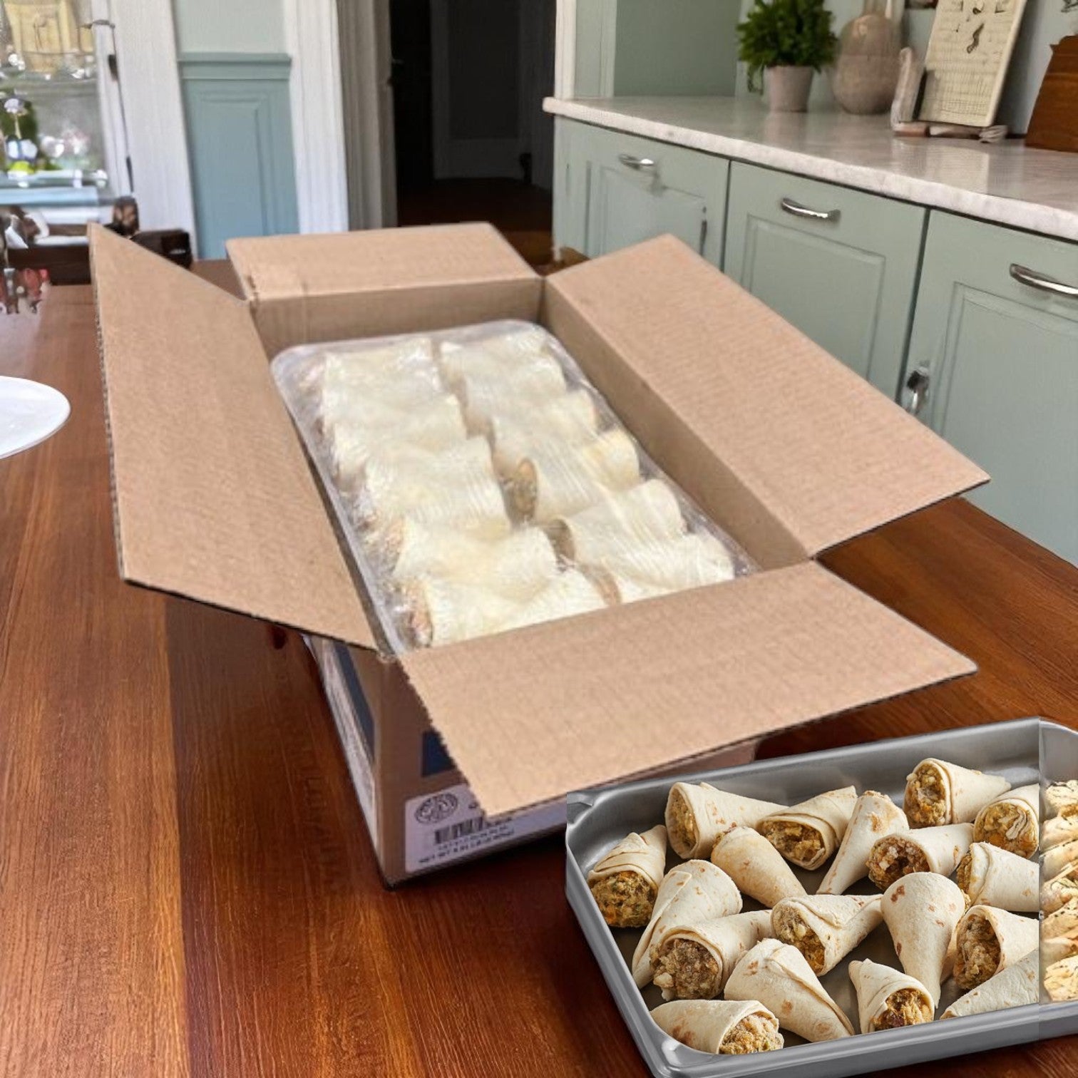 An open cardboard box filled with individually wrapped Sysco Reliance™ Mozzarella Cheese Sticks (Battered), 6 bags of 2 lbs each, sits on a wooden kitchen counter next to a tray of unwrapped cheese sticks.