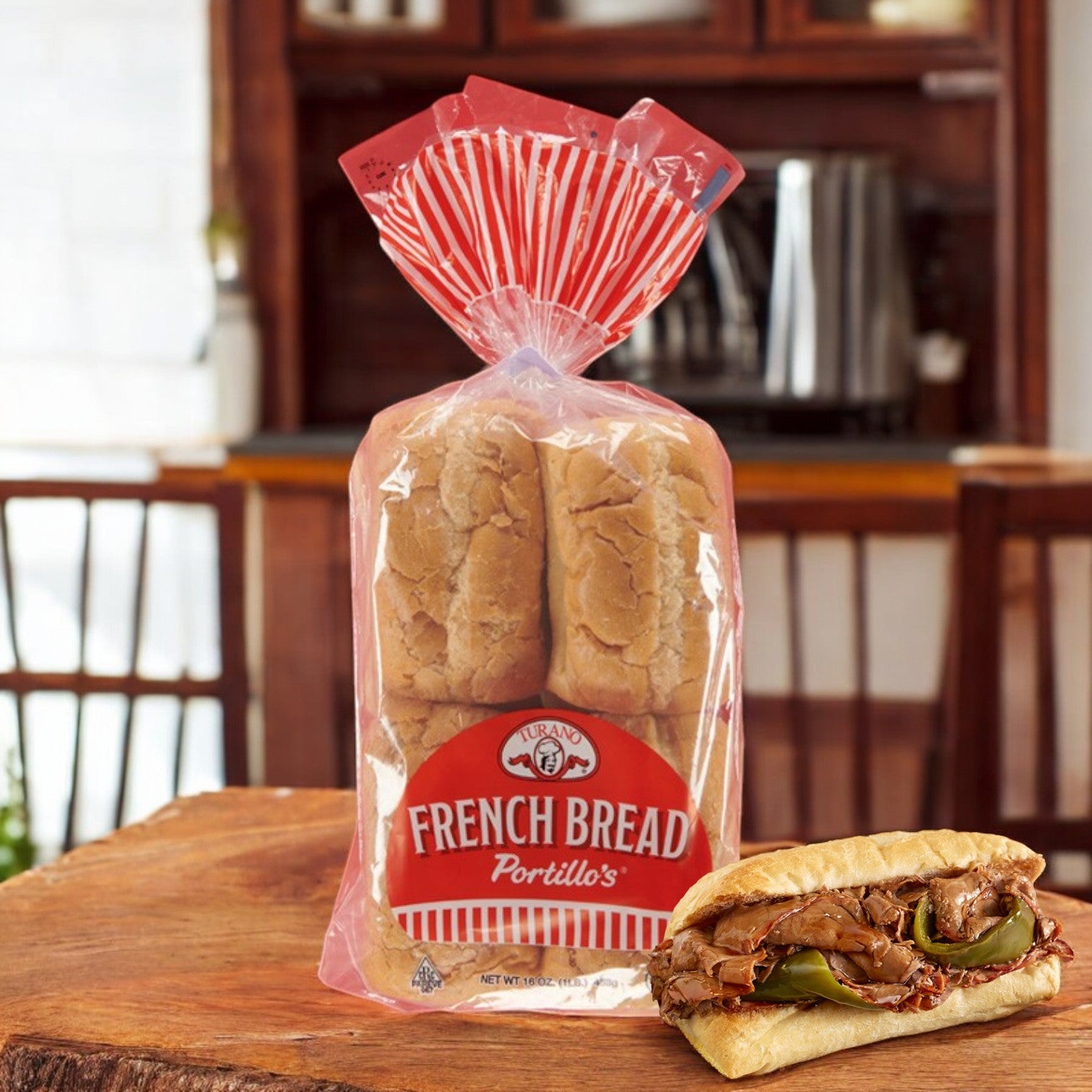 Portillo's French Bread – 16 oz, 8 Pieces 🥖 rests on a wooden table, its golden crispy crust inviting. Nearby, a mouthwatering beef sandwich tempts. A wooden chair and kitchen create a cozy backdrop.
