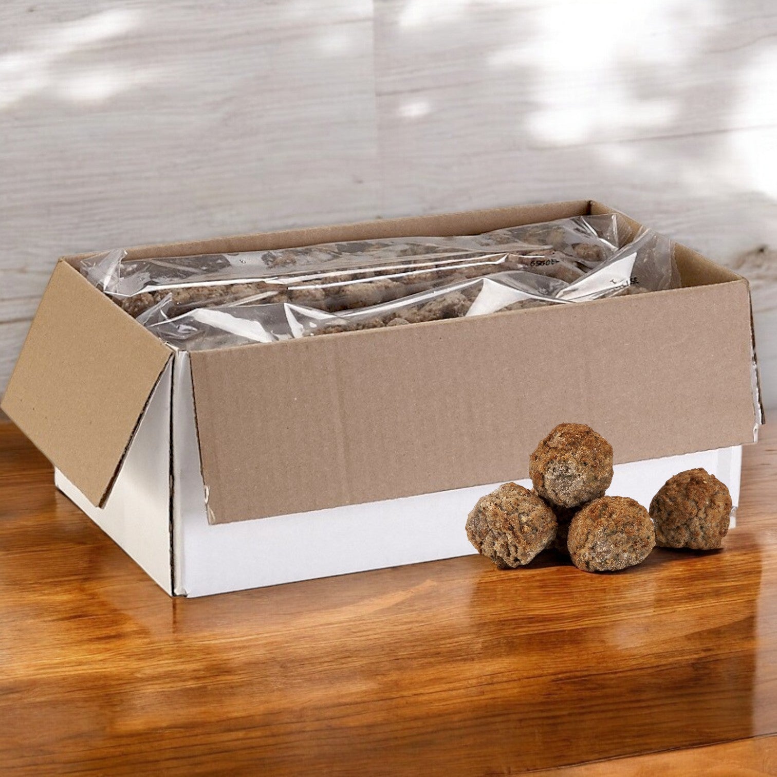 On a wooden table, an open box reveals clear bags containing Rosina Halal Beef & Chicken Meatballs. Three meatballs sit beside it, promising authentic Italian flavor for your meal.