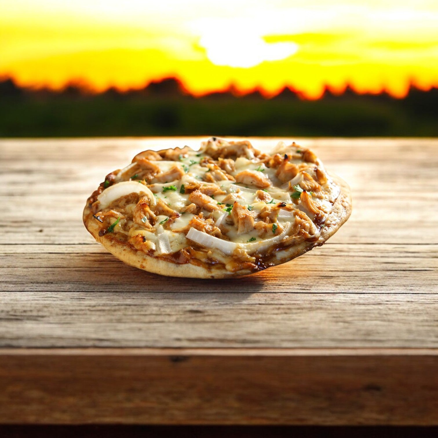 A Sysco Classic pizza with their low sodium Diced Chicken Meat, 0.5 Inch White & Dark, sits on a wooden surface against a sunset backdrop, offering a fully cooked meal that's delicious and health-conscious.