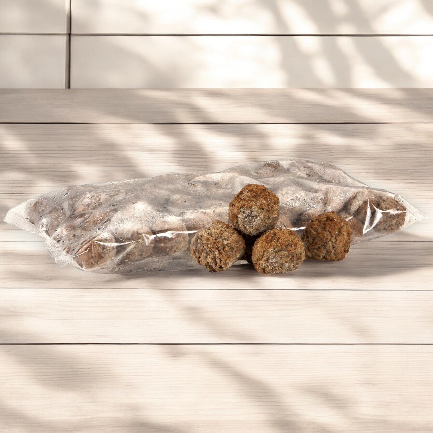 On a wooden table, a plastic bag of Rosina Halal Beef & Chicken Meatballs is displayed. Five gluten-free meatballs lie in front, boasting authentic Italian flavor, while nearby leaves cast shadows.
