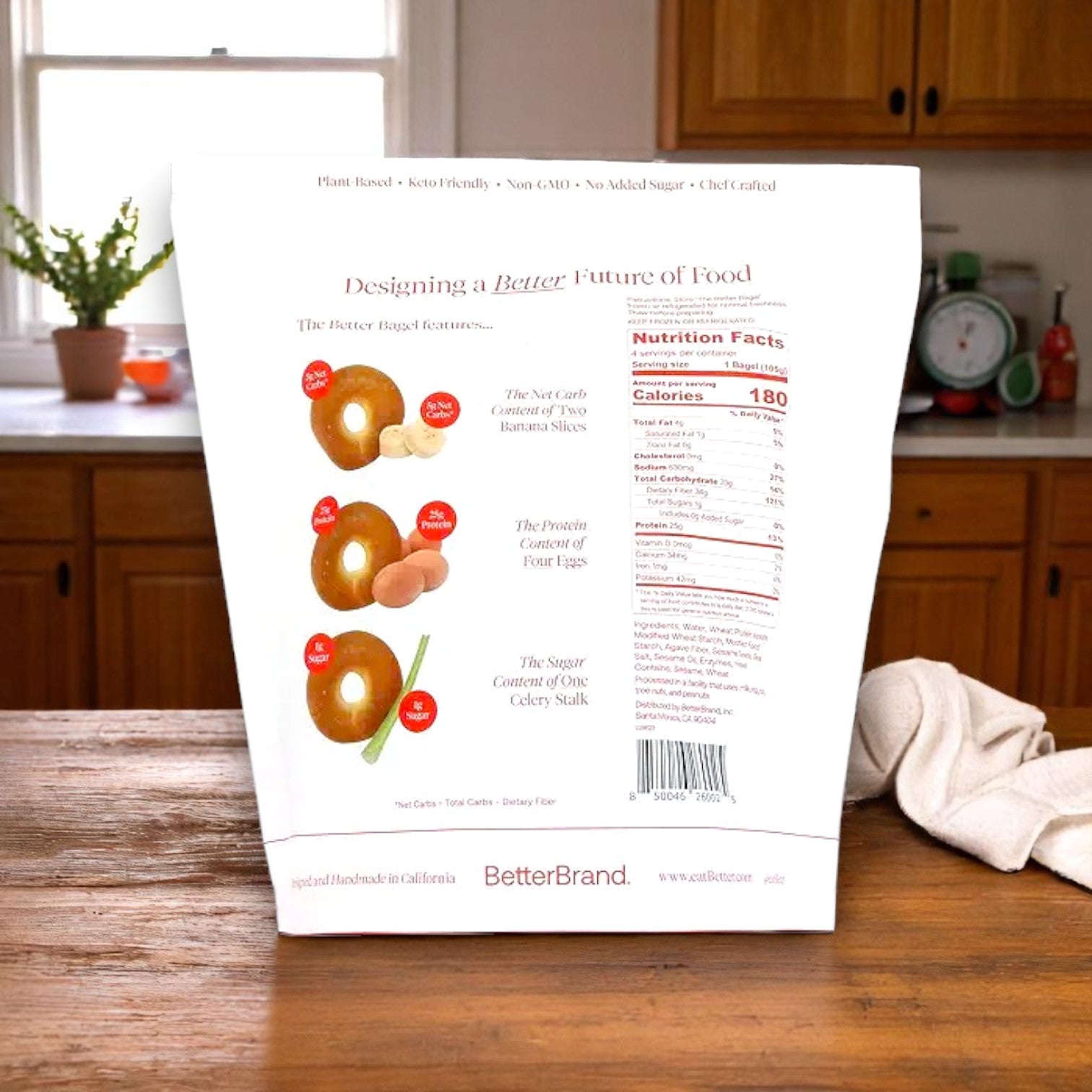 A bag of BetterBrand's The Better Bagel – Sesame Style sits on a kitchen counter, featuring nutrition facts and food comparisons—ideal for anyone wanting a high-protein bagel. Four bags (16 bagels) are in stock and ready to ship!.