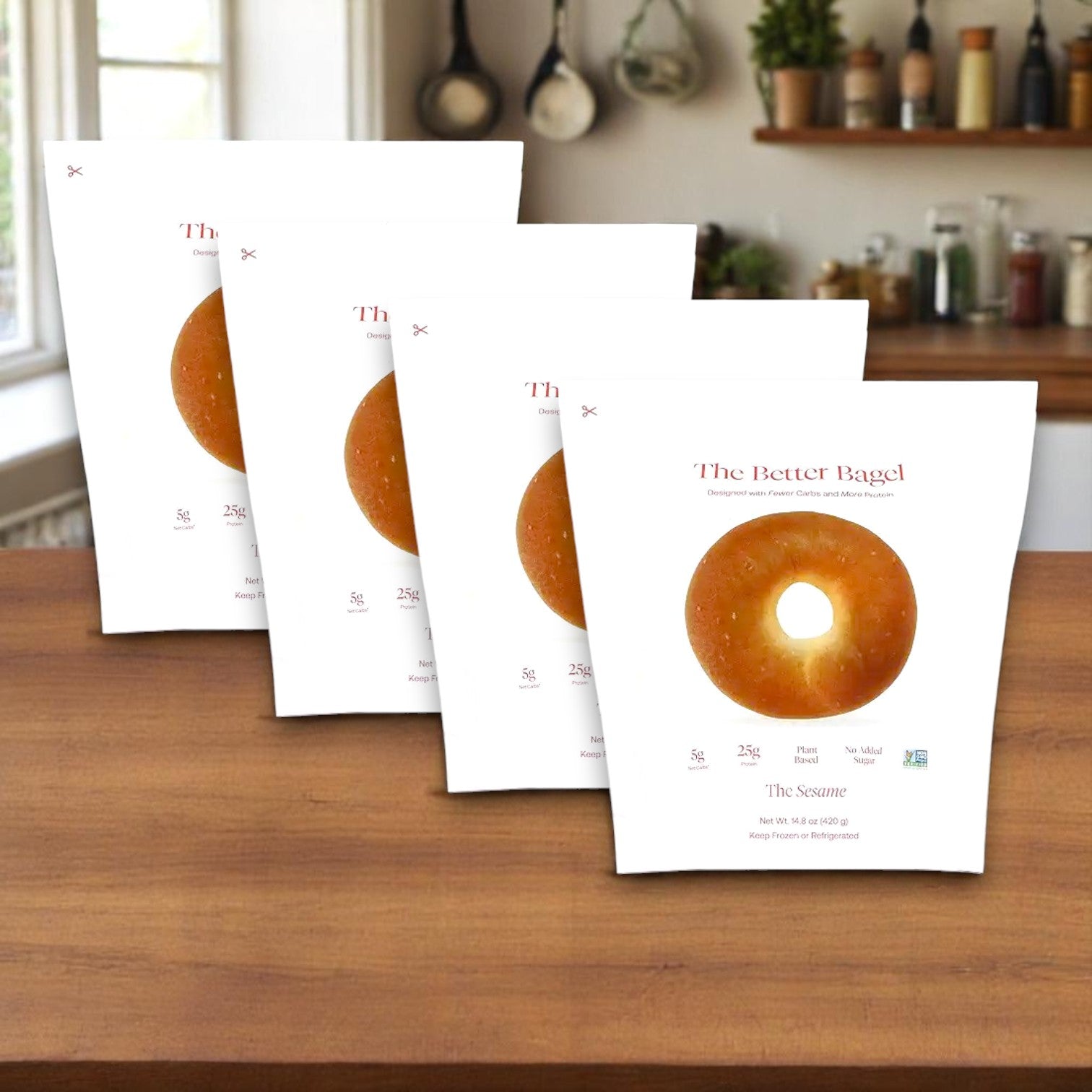 Four bags of BetterBrand's The Better Bagel – Sesame Style (16 bagels total) are displayed on a kitchen counter, each package featuring a sesame bagel image. In stock and ready to ship!.