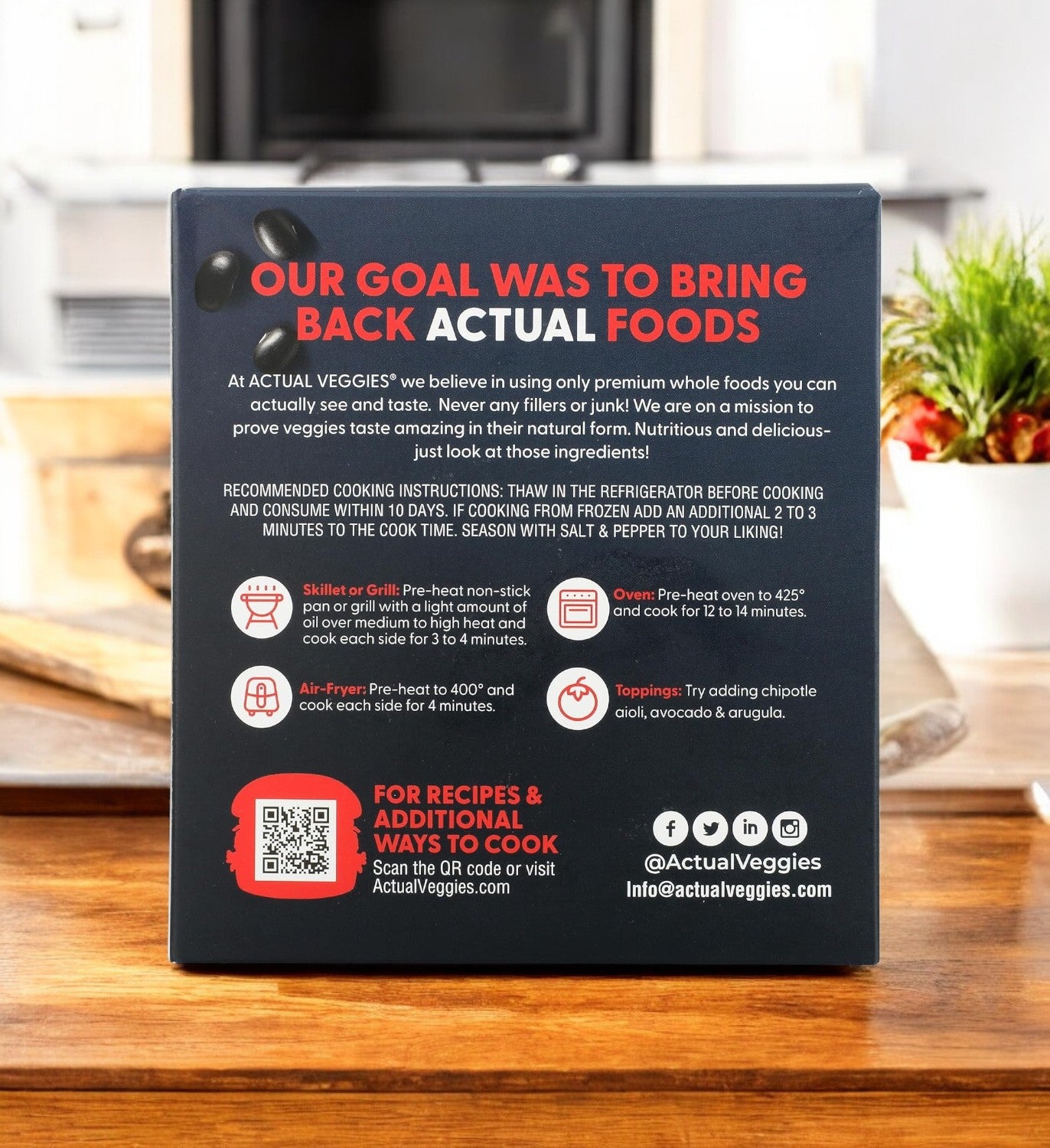 On a wooden table sits the Actual Veggies Black Bean Burger - 3 Count package, featuring preparation instructions and social media icons, showcasing our sustainable meal options.