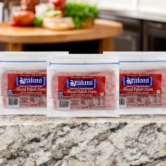 Three packs of Krakus Sliced Polish Ham - 16 Oz- 3 Count are beautifully showcased on a marble countertop in a kitchen, ideal for making sandwiches as tasty as any recipe.