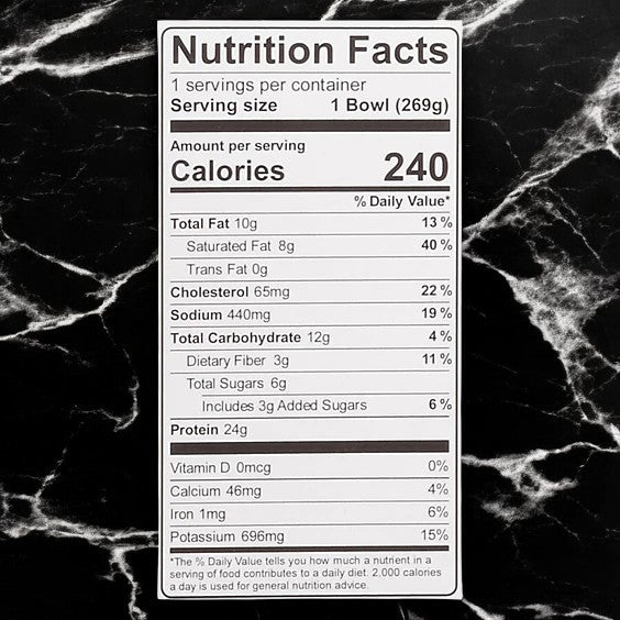 Kevin's Natural Foods Thai-Style Coconut Chicken (3 Count) nutrition label shows 240 calories per 269g bowl, with fat, cholesterol, sodium, carbs, protein, vitamins, calcium, iron & potassium—gluten-free and paleo-friendly—on a black marble surface.