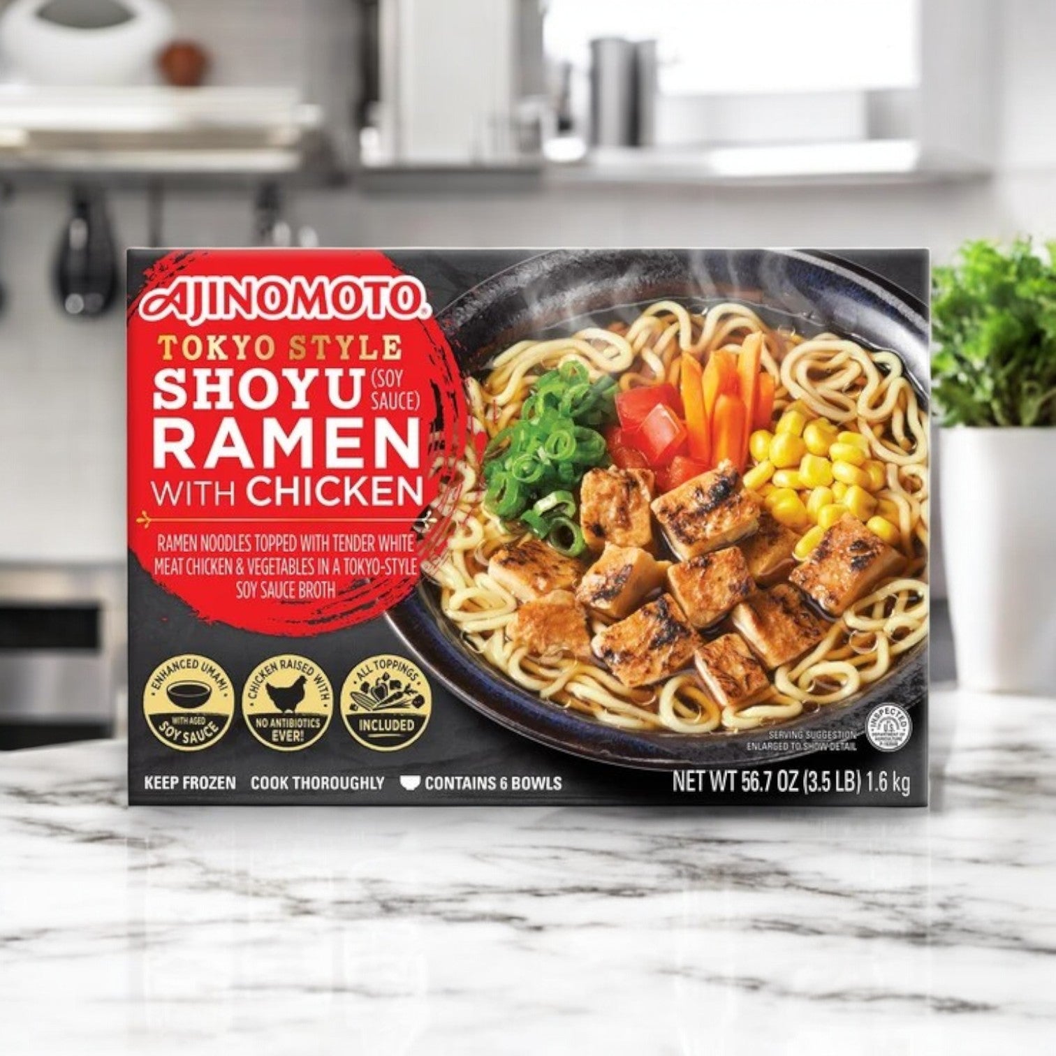 A 56.7 oz box of Ajinomoto Shoyu Ramen with Chicken is displayed on a marble counter, featuring savory umami flavor and eye-catching packaging that highlights this authentic Japanese-style ramen by Ajinomoto.