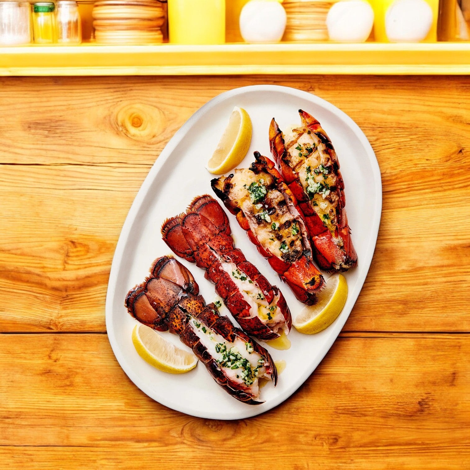 Four cooked Member's Mark Warm Water Lobster Tails from Easy Lunches are arranged on a white plate with lemon wedges—ideal for entertaining. Available frozen in a 4-count, 3-pack at Sam's Club.