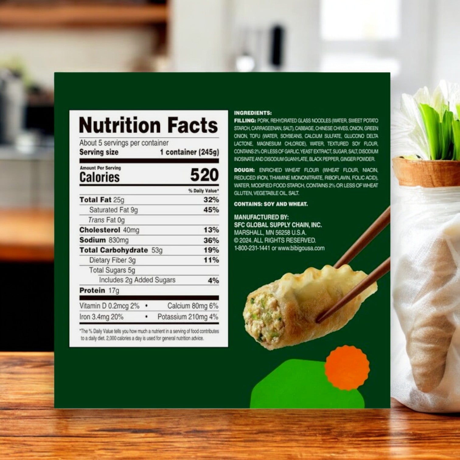 A Bibigo Mandu Pork & Vegetable Dumpling (32 oz, 3 Packs) box with nutrition facts and ingredients is shown on a wooden surface, while chopsticks hold a dumpling in the foreground.