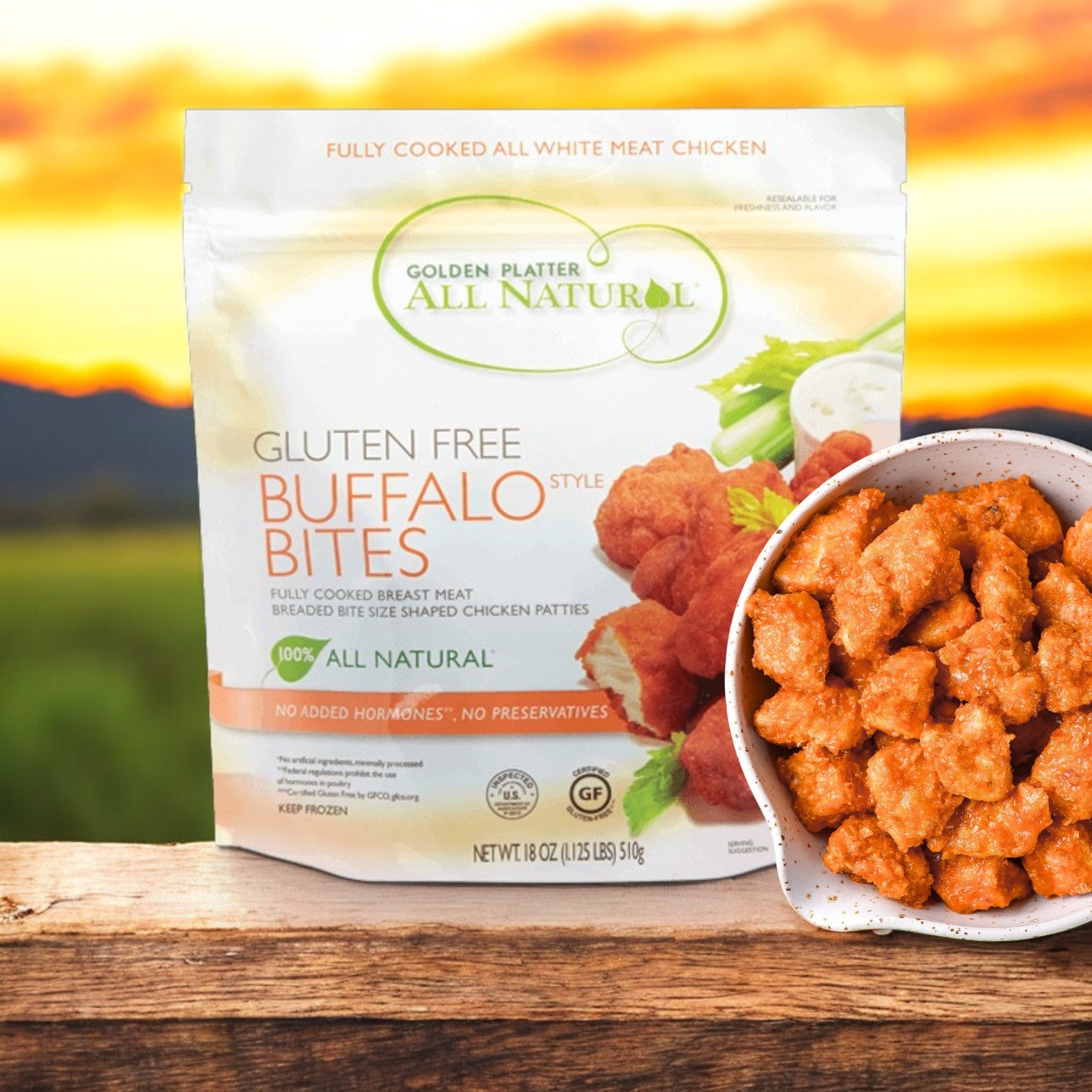 A package of Golden Platter All Natural Gluten Free Buffalo Style Bites (24 Count) sits next to a bowl of the spicy, all natural snack, both displayed on a wooden surface.