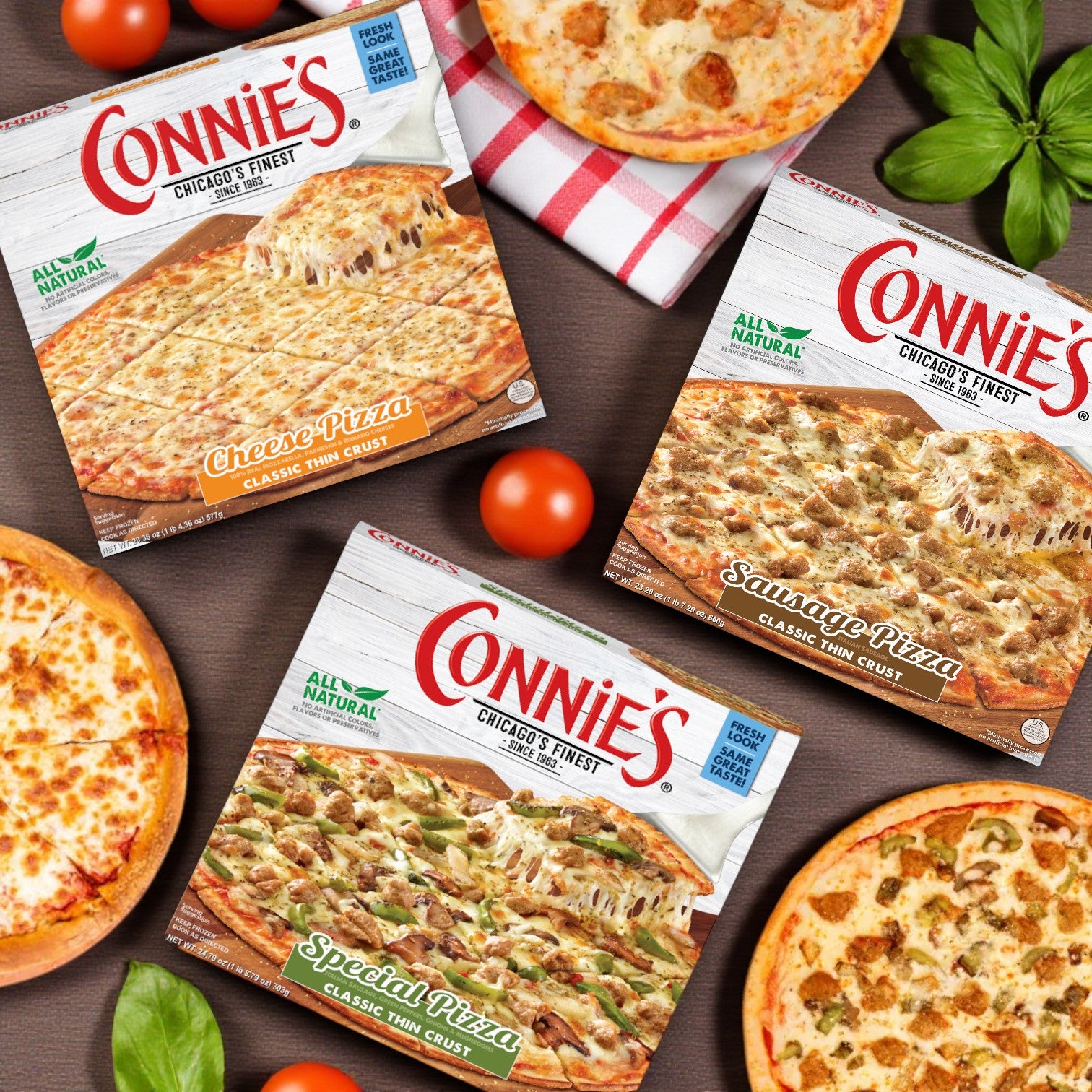 Three Connie's Pizza Classic Thin Crust Combo – 3 Pack! boxes from Connie's Pizza are displayed on a table with whole tomatoes, basil leaves, and classic Chicago-style pizzas.