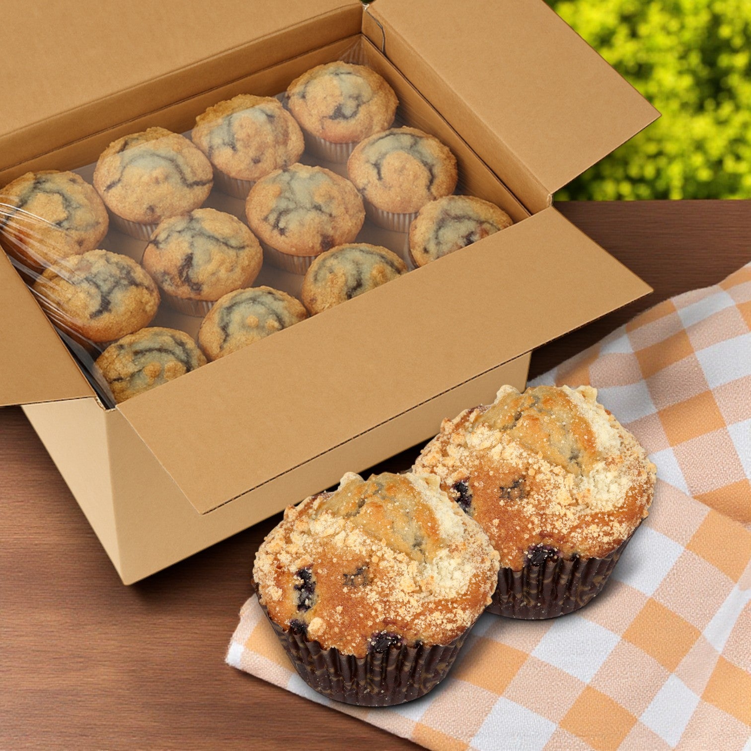 A box of Chef Pierre Blueberry Muffins – 48 Count / 4.25 oz Each sits on a wooden surface outdoors, with two muffins up front—delicious grab-and-go snacks from Chef Pierre for any occasion.