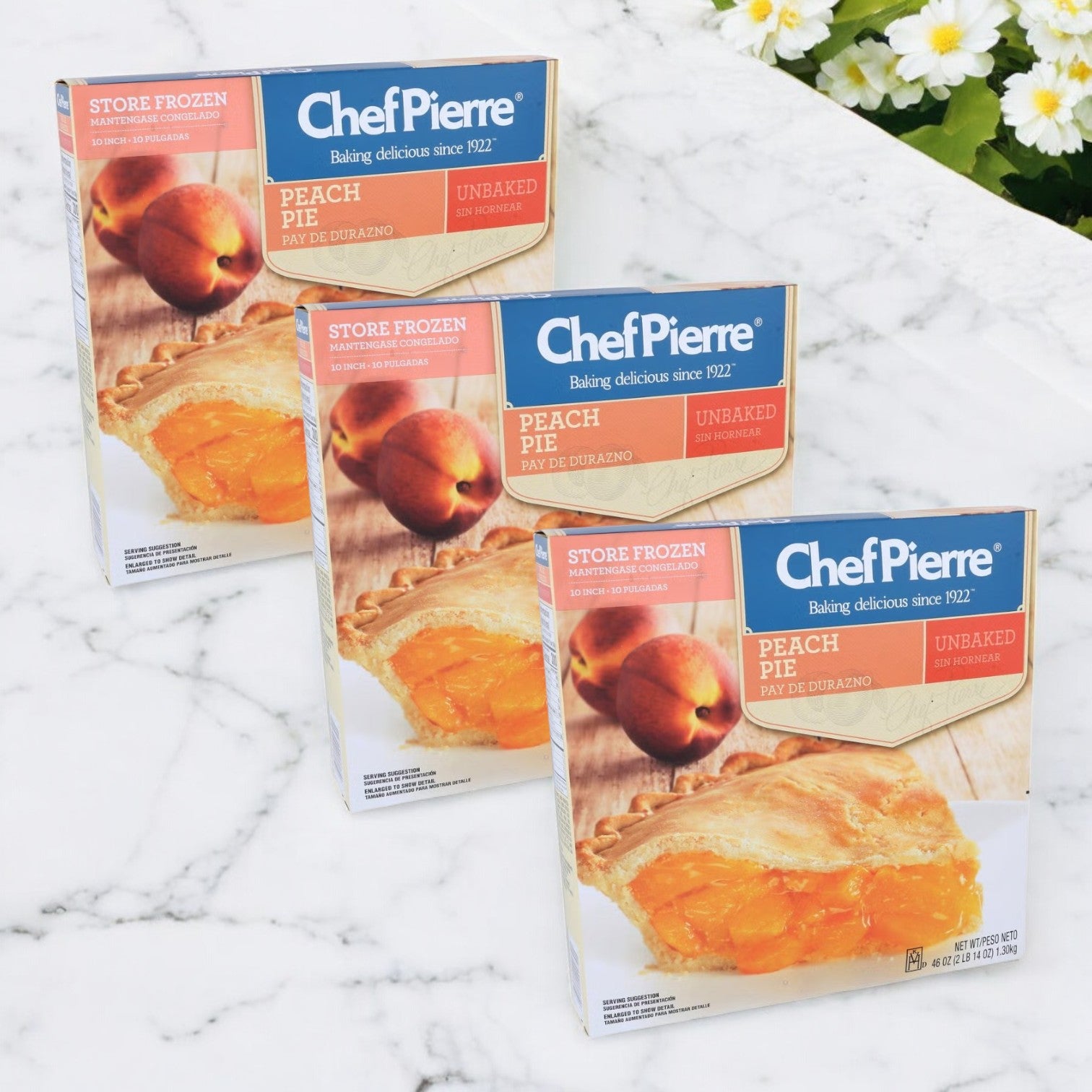Three boxes of Chef Pierre Peach Pie, 46 oz each, are arranged on a white marble surface, poised to become freshly baked delights.