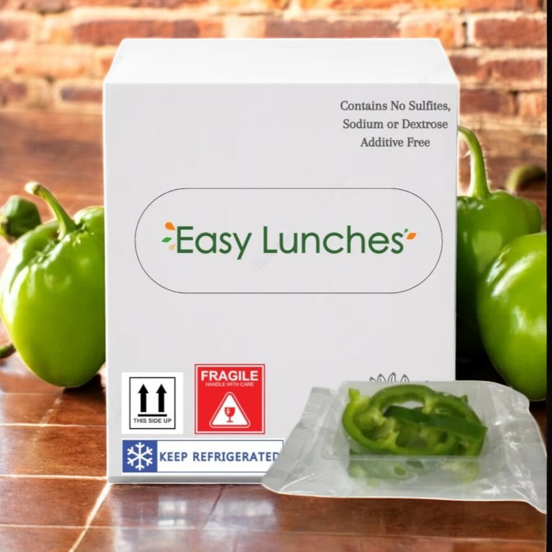 An Easy Lunches box sits on the counter, with fresh ingredients. Vibrant green bell peppers add to the background, while a sealed packet of Green Pepper Julienne, 2.5 oz., takes center stage in the foreground.