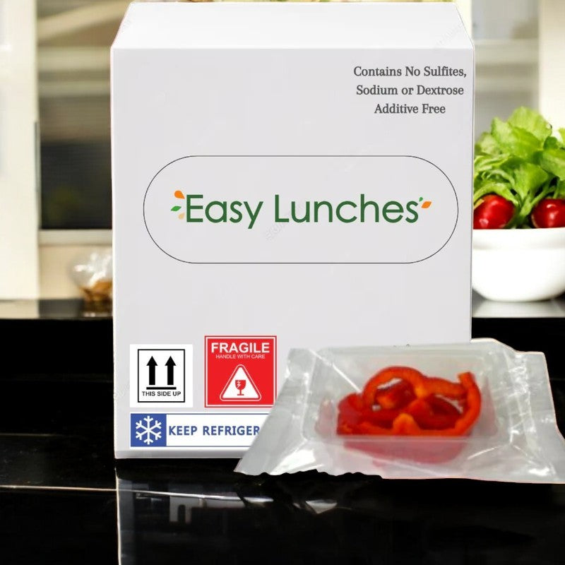 A box from Easy Lunches labeled "Sliced Red Peppers, 2.5 oz. - 50 Pack" is placed next to a package of nutritious peppers. It bears labels "Fragile," "Keep Refrigerated," and boasts that it contains no sulfites, sodium, or dextrose.
