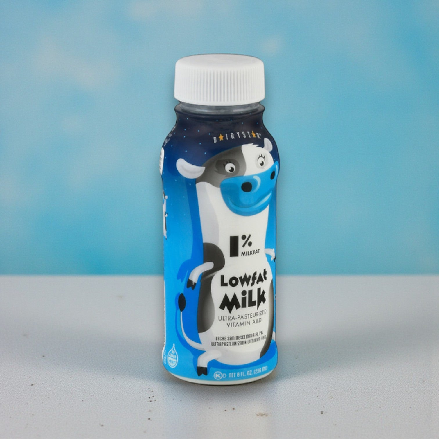 An 8 oz Dairy Star Low Fat 1% Milk bottle, featuring a cartoon cow on the label, sits on a light surface against a blue background.