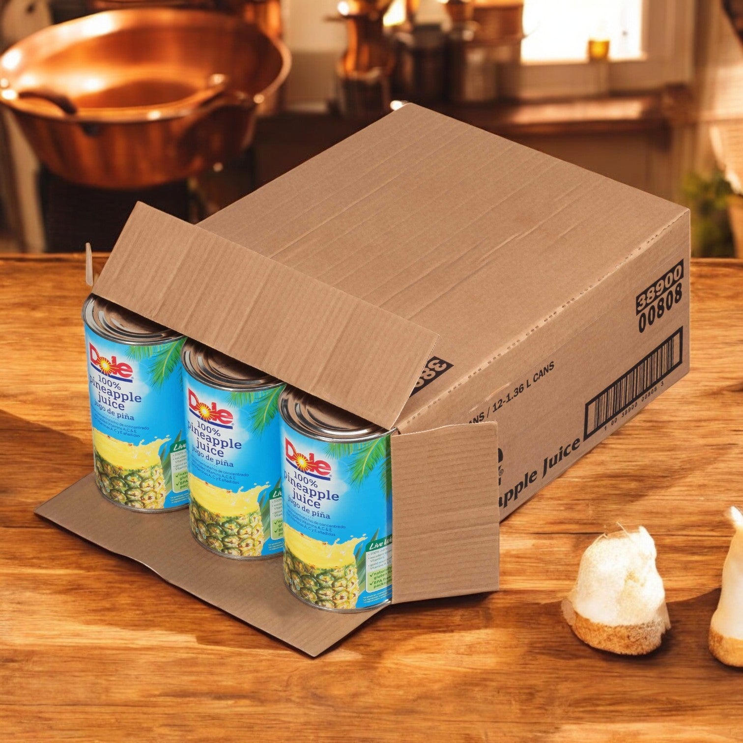 A partially opened cardboard box of Dole 100% Pineapple Juice – Not From Concentrate (12/46 oz cans) sits on a wooden kitchen counter.