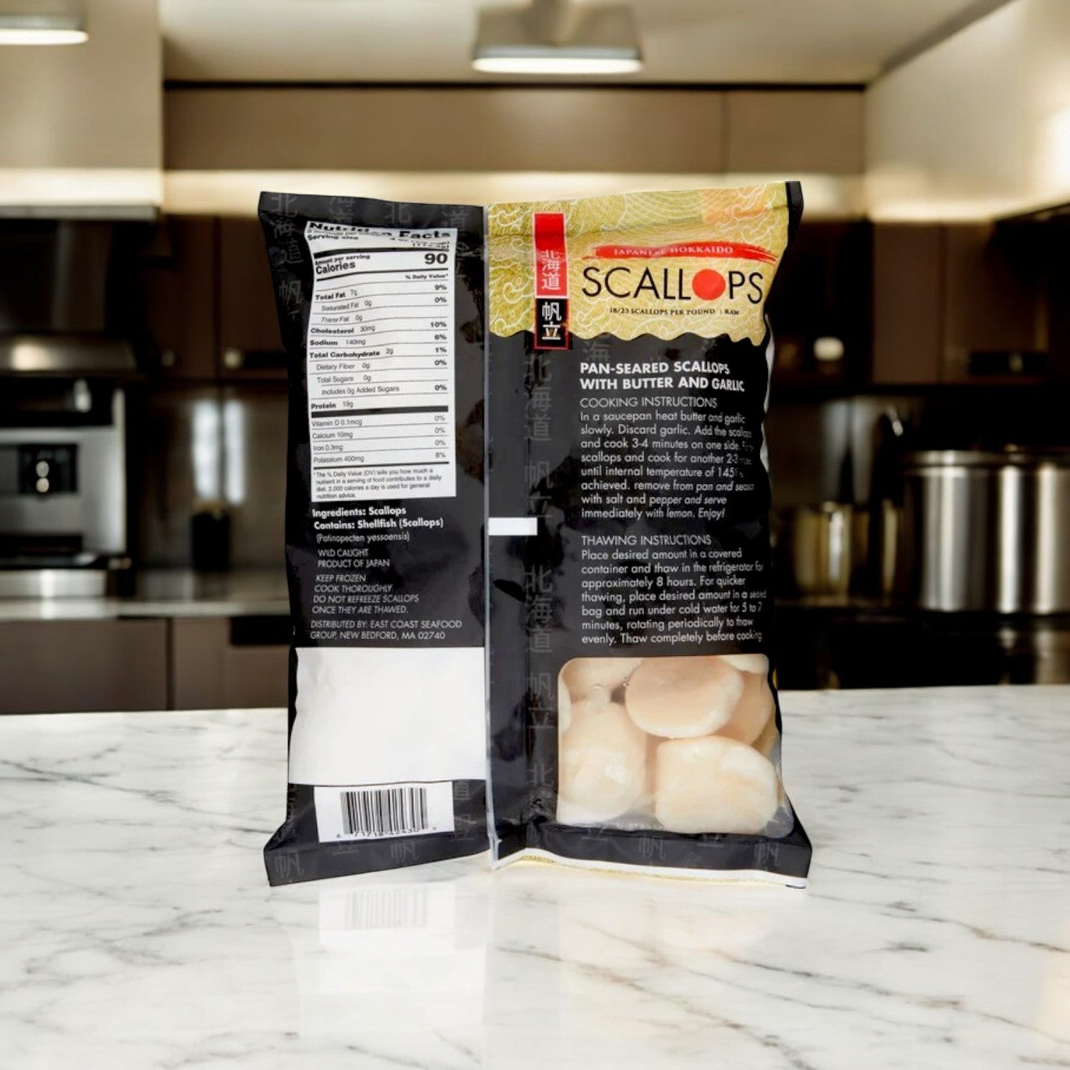 Two packs of Kirkland Signature East Coast Seafood Japanese Hokkaido Scallops, Raw, 18-23 ct, 2 lbs are displayed on a marble countertop; one shows the nutrition label, the other highlights the premium scallops packaging.