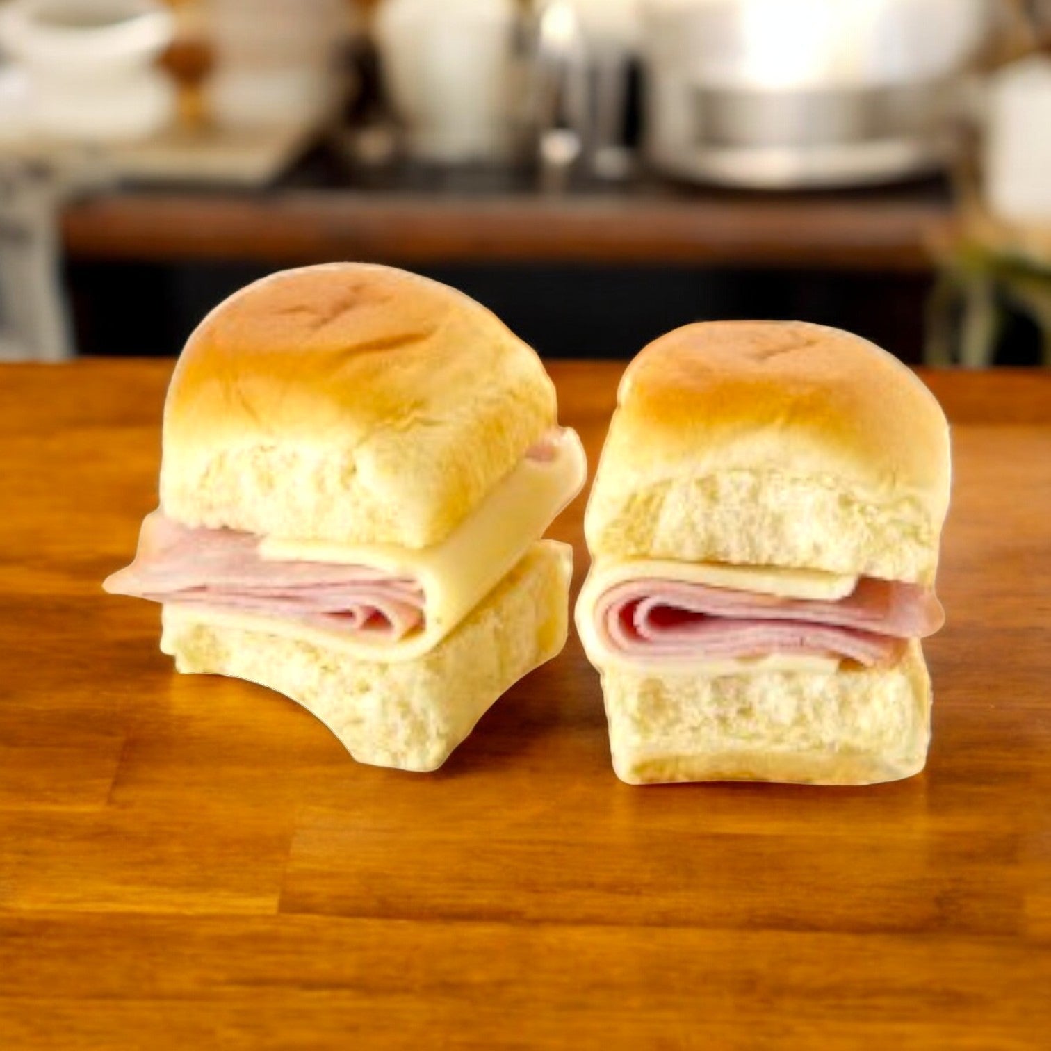 E.A. Sween's Smoked Ham and Swiss Sliders, which ship frozen with a 30-day cooler shelf life, are displayed on a wooden surface with a blurred kitchen backdrop.