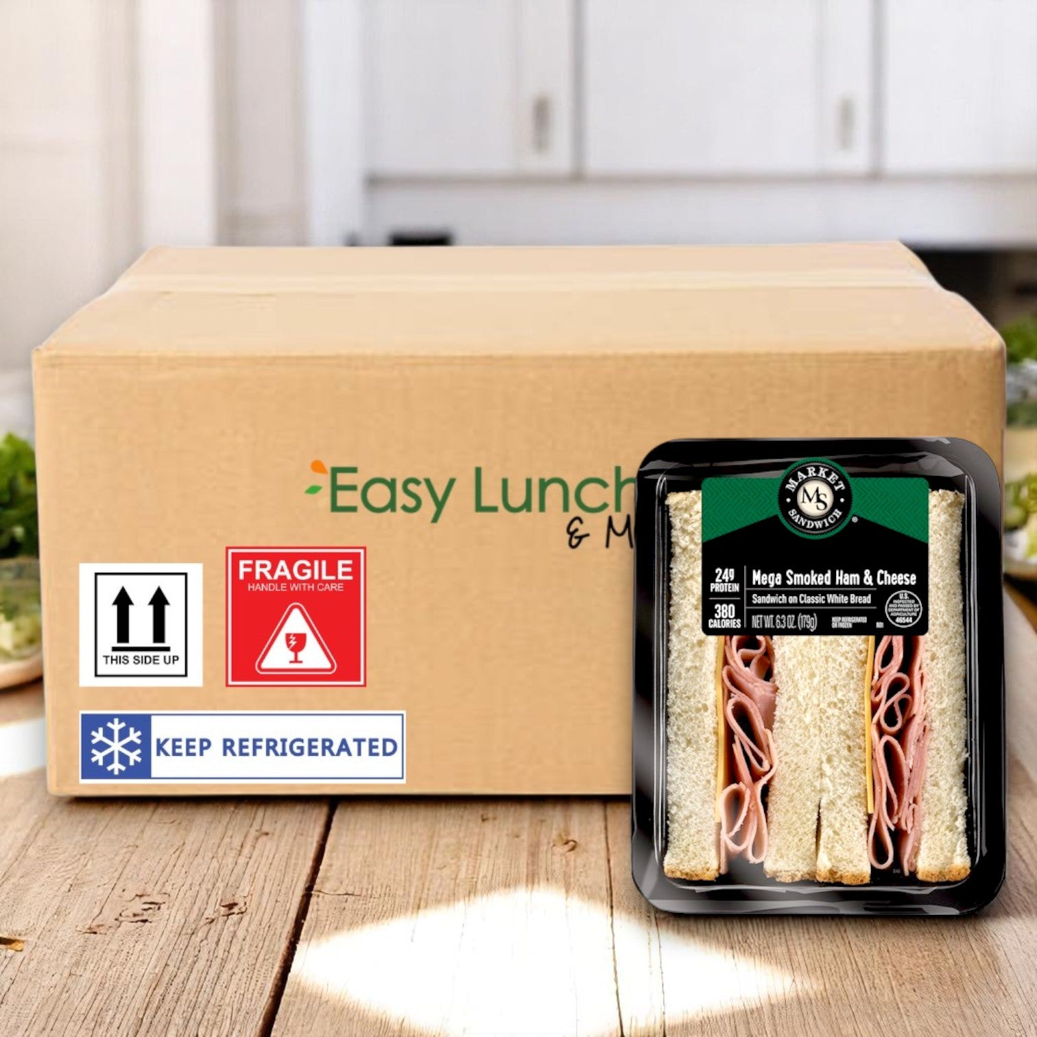 A cardboard shipping box labeled "E.A. Sween" with a Market Mega Smoked Ham & Cheese Sandwich Wedge – 6.3 oz (8 Per Case) beside it, plus "Fragile," "Keep Refrigerated" stickers and handling symbols on the box.