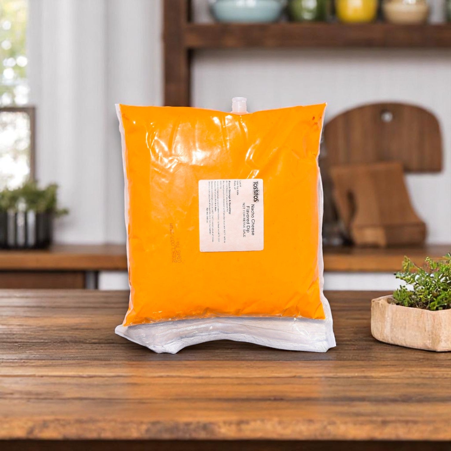 A 140 oz bag of Tostitos® Nacho Cheese Sauce (Pack of 4) sits on a wooden table, offering a convenient bulk option from Tostitos—ideal for catering or events.