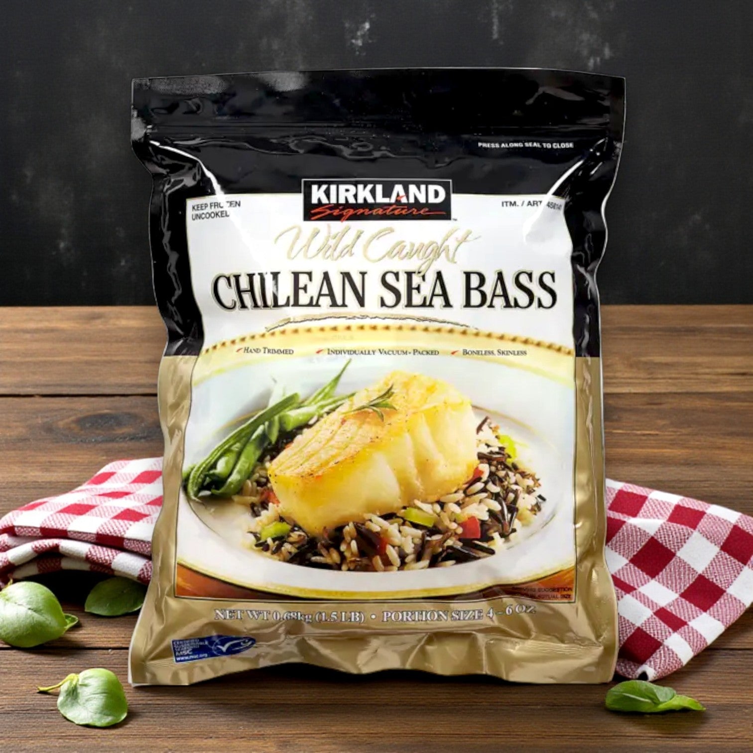Kirkland Signature Wild Chilean Sea Bass – 4–6 oz Portions (1.5 lbs Total) is shown on a table with a plate of food, a red-checkered napkin, and broad beans, emphasizing the premium appeal of this white fish from Kirkland Signature.