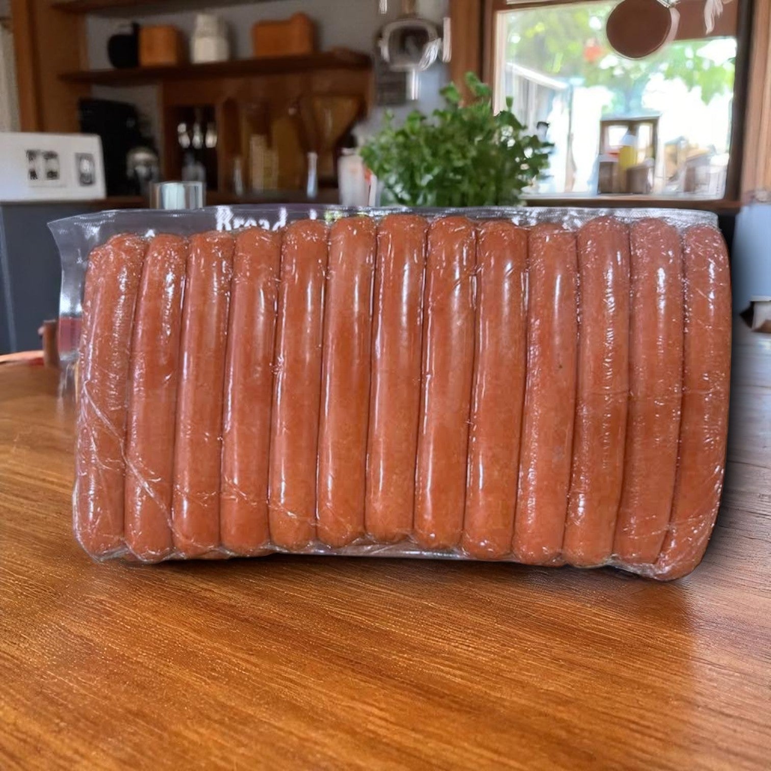 A sealed plastic package of Amylu Halal Hot Dogs–Leon's Sausage 8:1 Beef Hot Dogs, 5 lb pack (40 hot dogs), sits on a wooden table in a kitchen.