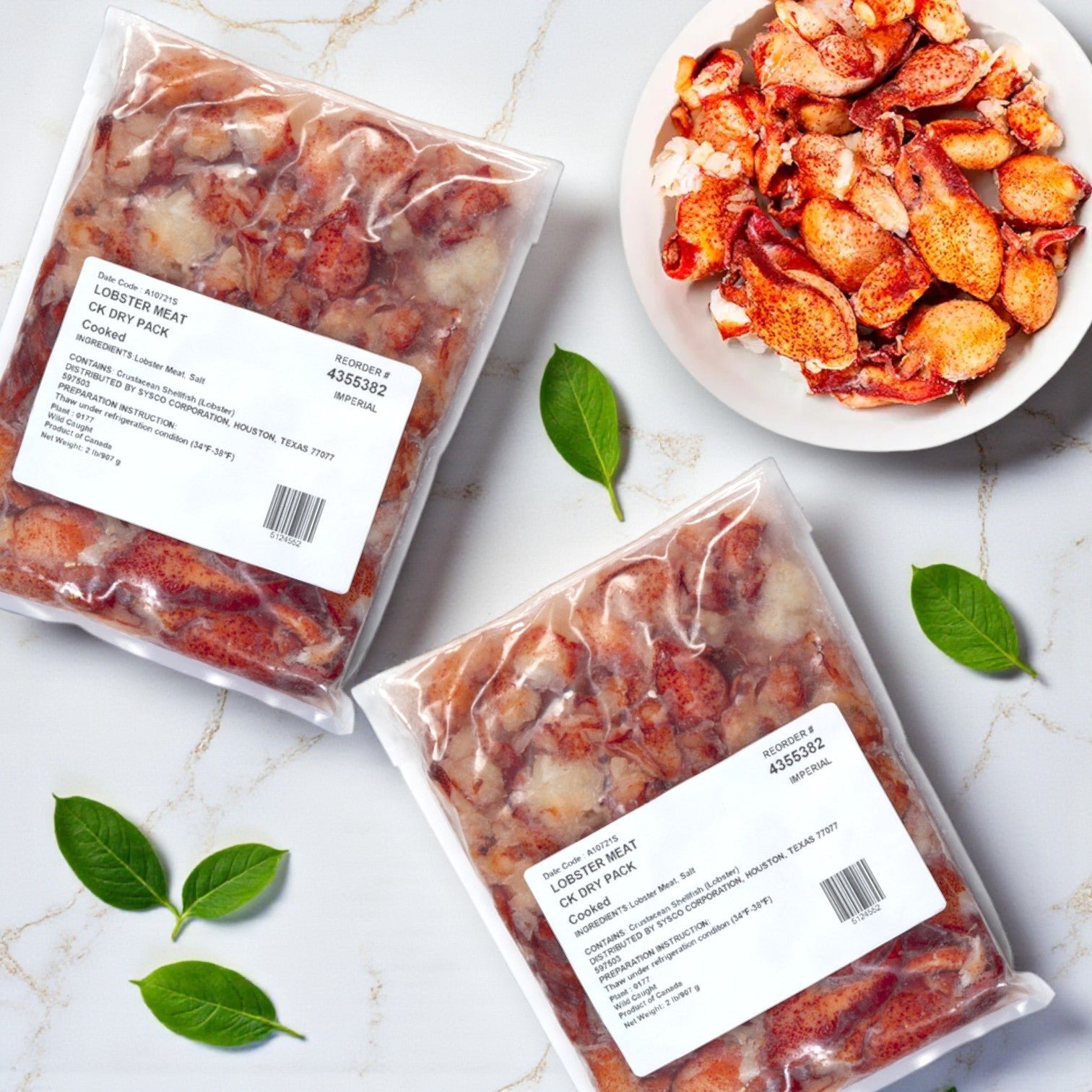 Two vacuum-sealed packs of Easy Lunches Maine Lobster Meat Claw and Knuckle (each 2 lbs, total 4 lbs) are displayed on a marble surface near a bowl of loose lobster meat, with green leaves scattered around.