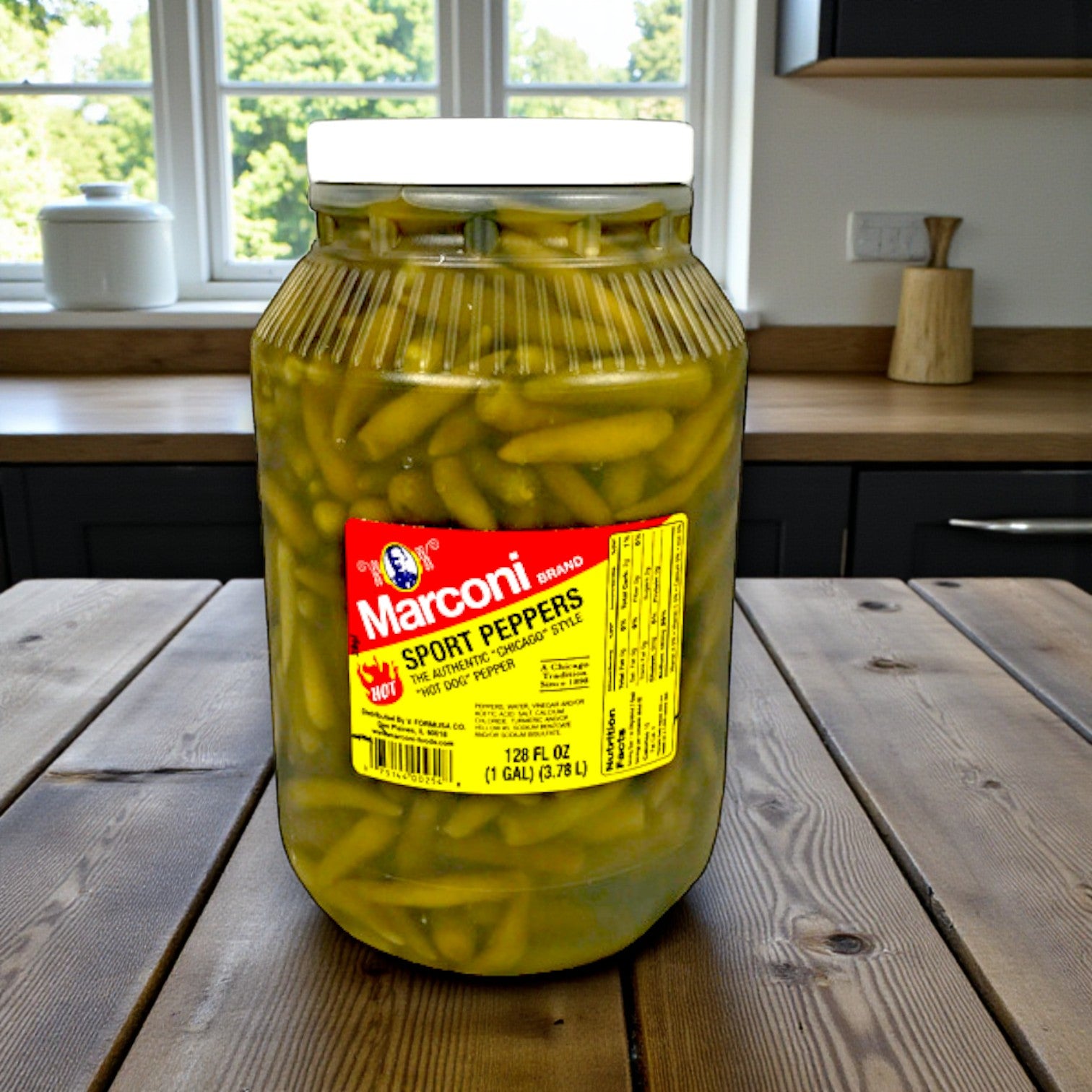 A 1-gallon jar from the Marconi Sport Peppers 4-Pack by Macroni Foods adds bold Chicago-style flavor on a wooden kitchen counter with sleek cabinets and a window in the background.