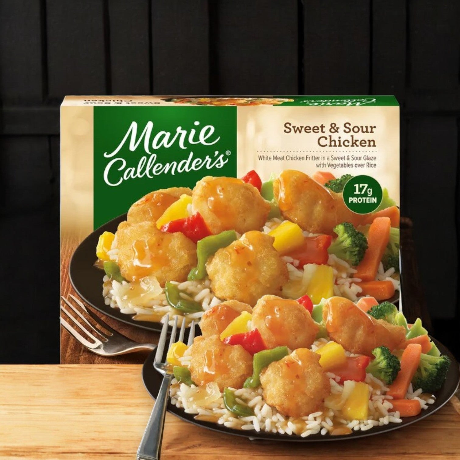 The Marie Callender's Sweet & Sour Chicken Frozen Meal, 14 oz., by Marie Callender's, presents a delightful culinary experience with tender chicken, rice, and colorful vegetables elegantly arranged on a black plate complete with a fork.