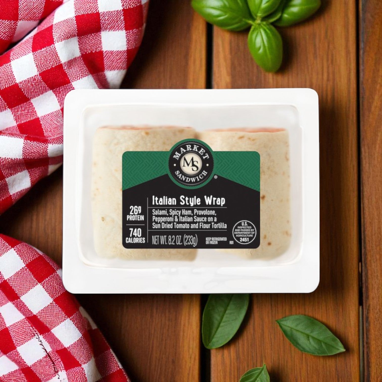 An E.A. Sween Market Wrap Combo Pack—featuring 4 Italian Style Wraps (8.2 oz) and 4 Chicken Caesar Wraps (8.6 oz), all individually wrapped—rests on a wooden surface with fresh basil and a red-and-white checkered cloth for classic appeal.