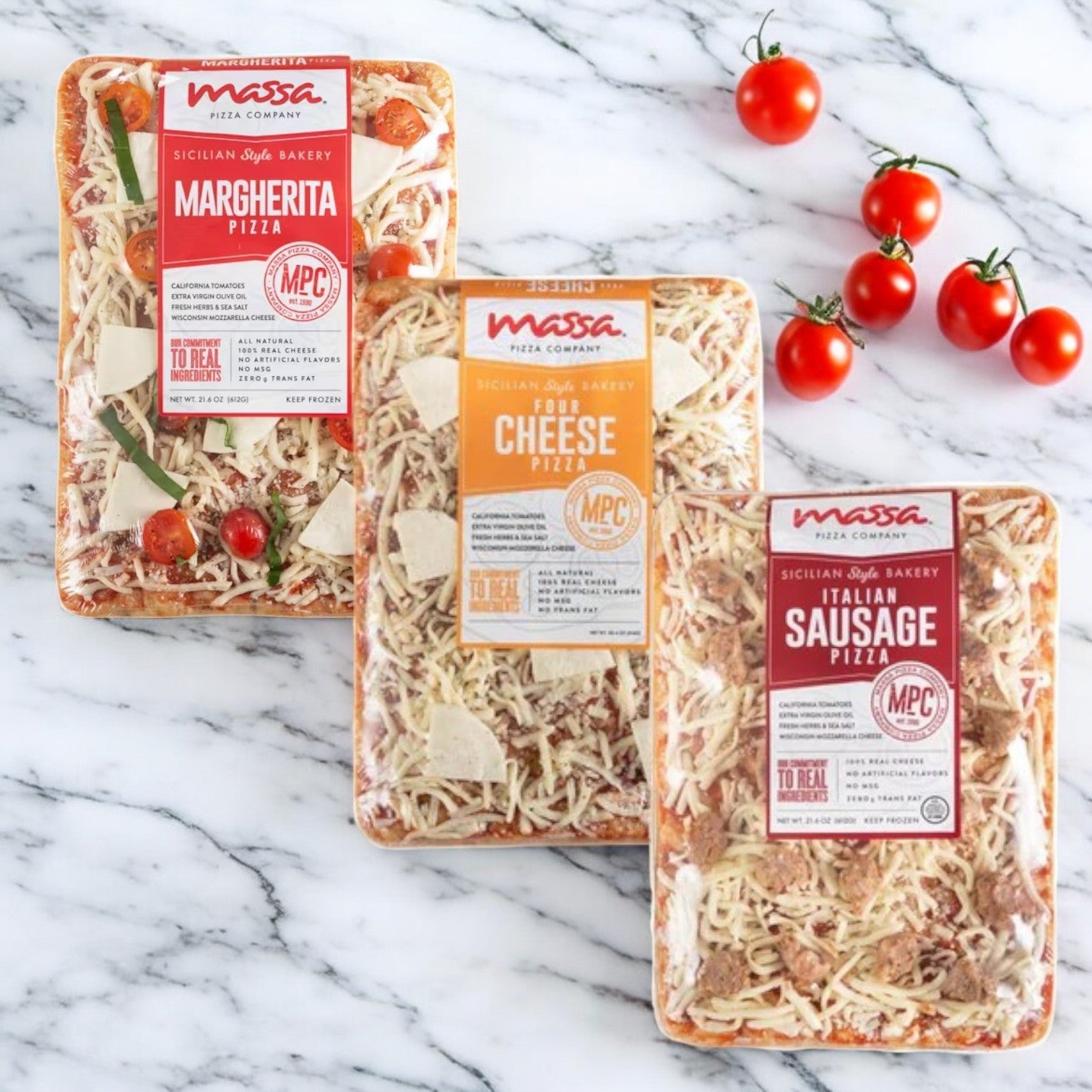 Three packs of Massa Pizza Co. 3 Pack Combo! from Massa Pizza are elegantly arranged on a marble surface, showcasing the Margherita, Four Cheese, and Italian Sausage flavors. The appetizing display is enhanced by the presence of cherry tomatoes nearby, accentuating the artisan bakery crust in each flavorful option.