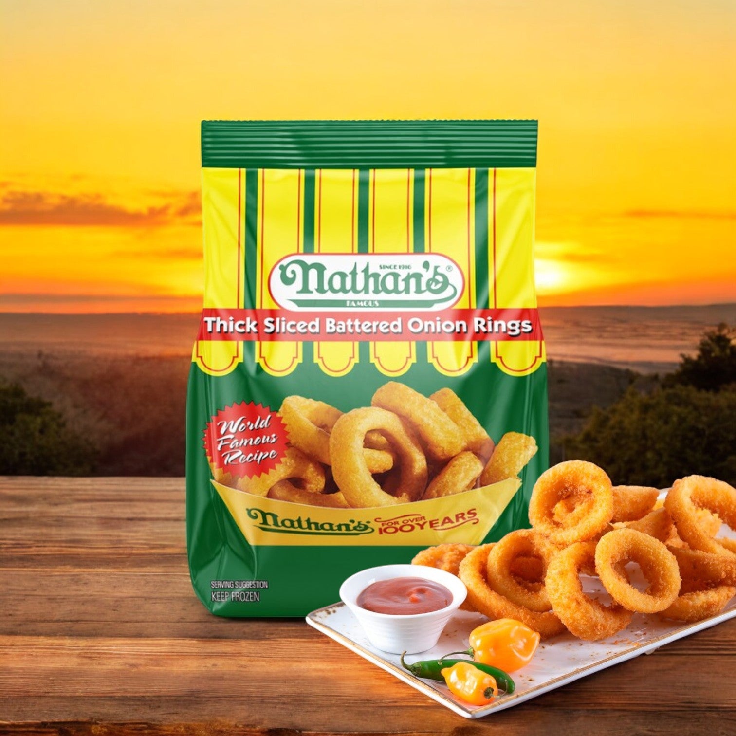 A 16 oz bag of Nathan's Famous Thick Sliced Battered Onion Rings is shown with a plate of crispy onion rings, dipping sauce, and peppers set against a sunset background.