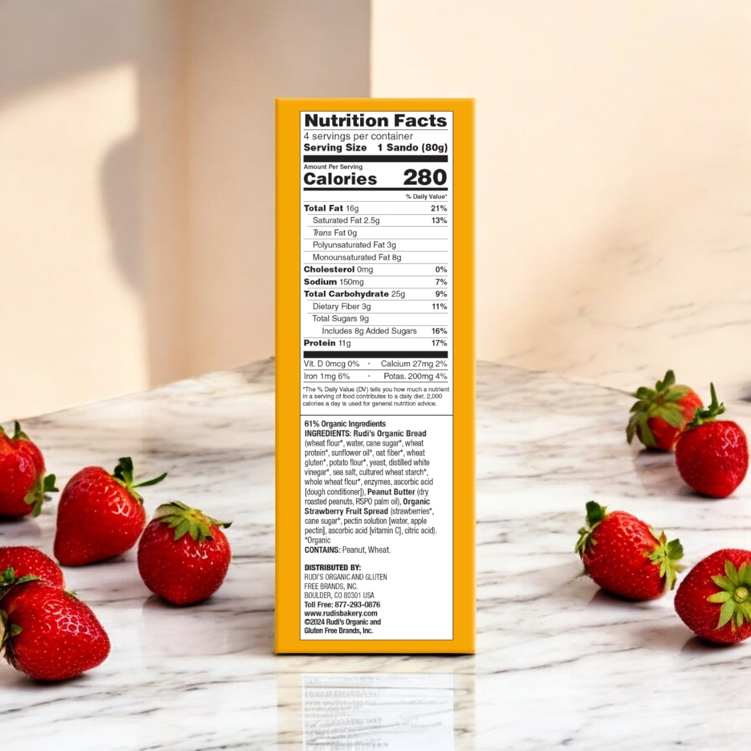 Nutrition facts label for Easy Lunches Rudi's Peanut Butter and Strawberry Spread Sandos, 11.2 oz (3 Packs), on a yellow box surrounded by fresh strawberries, sunlight, and shadows on a white surface.