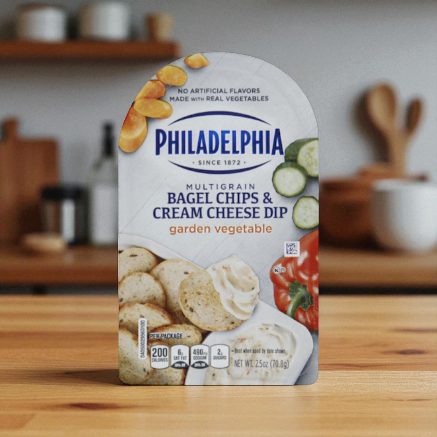A 2.5 oz. pack of Kraft Philadelphia Multigrain Bagel Chips & Garden Vegetable Cream Cheese Dip sits on a wooden kitchen counter.