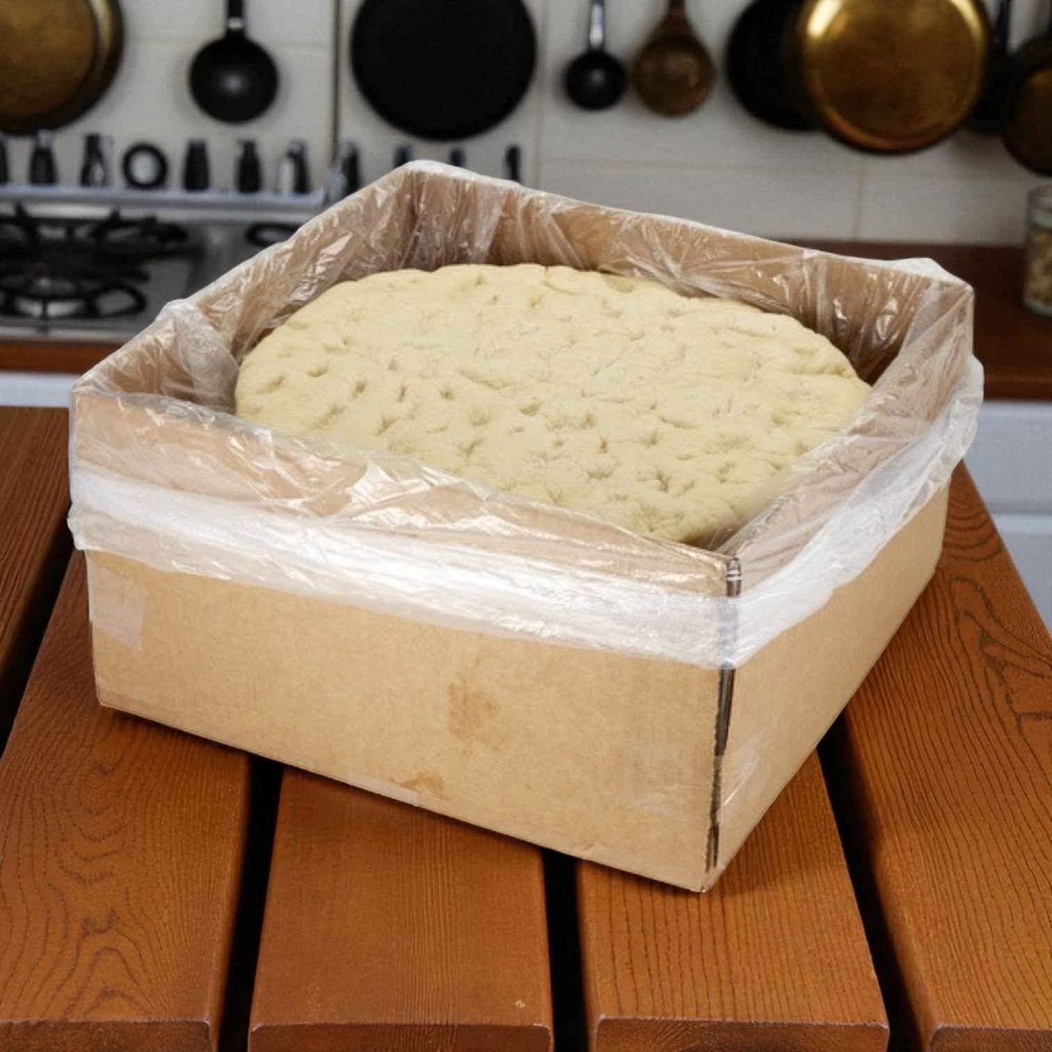 A box of Sysco Fontanini Rustic Parbaked Pizza Crusts, 16" size and 24 oz each (12 count), sits on a kitchen table, ready to be topped and baked.