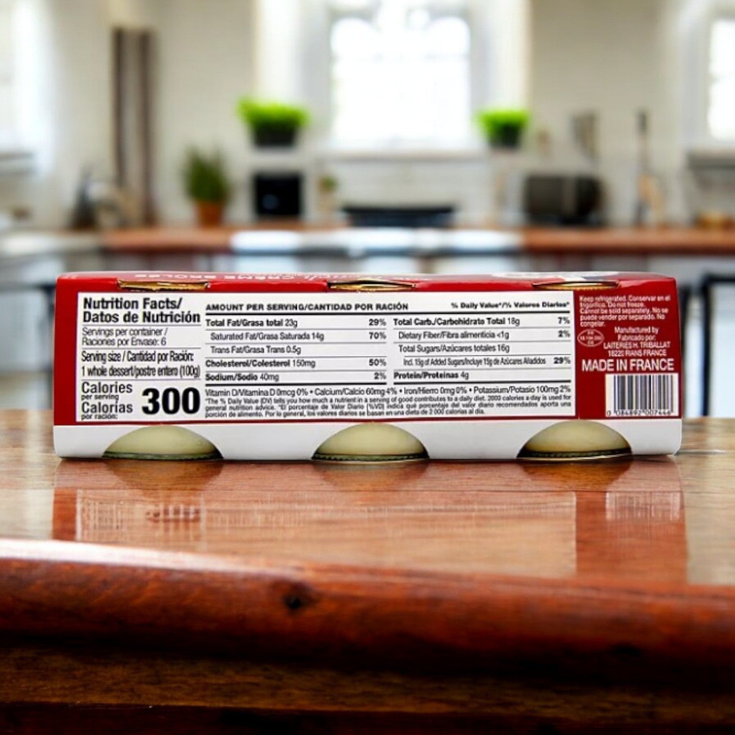 A box of Rian's La Crème Brûlée, featuring nutrition facts and perfect for crafting classic French desserts, contains 18 packs at 300 calories per serving. Nestled on a wooden counter with a blurred background, the "Made in France" label stands proudly.