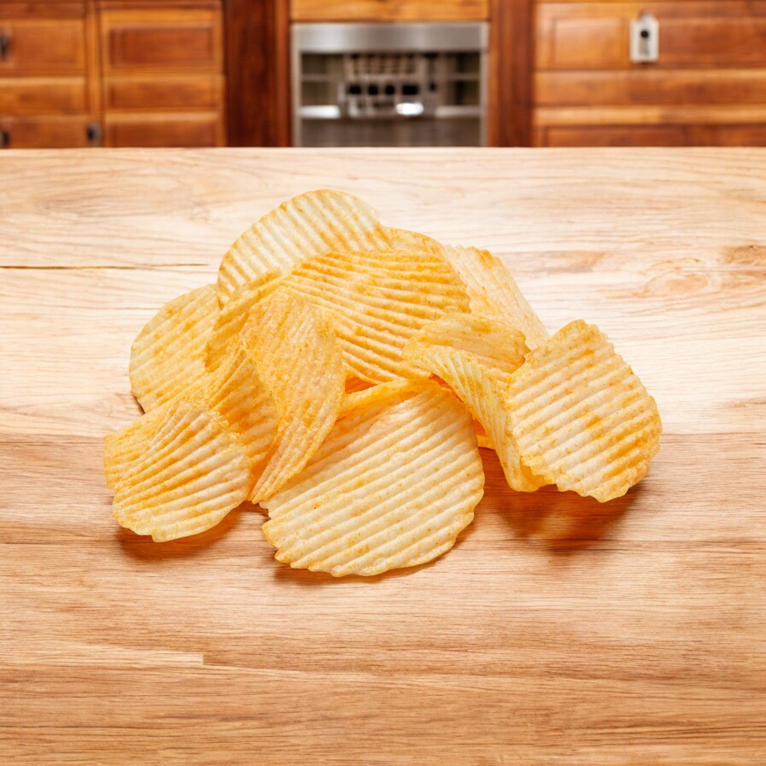 A tempting pile of Ruffle's Potato Chips, Cheddar & Sour Cream Flavored (1 oz, 50 pk), sits on a wooden countertop in a kitchen with wooden cabinets in the background, ready to enjoy as a savory snack.