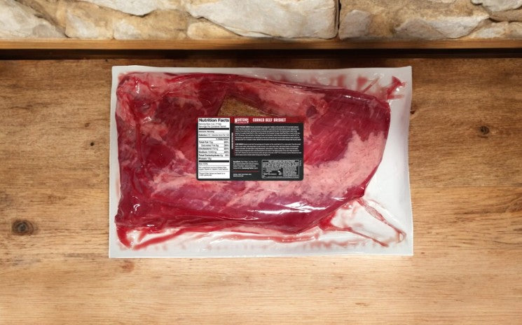 A vacuum-sealed Morton's Of Omaha Corned Beef Brisket (4 lbs, 3 packs) sits on a wooden surface—ideal for St. Patrick’s Day or slow cooking—with a visible nutrition label on the package.
