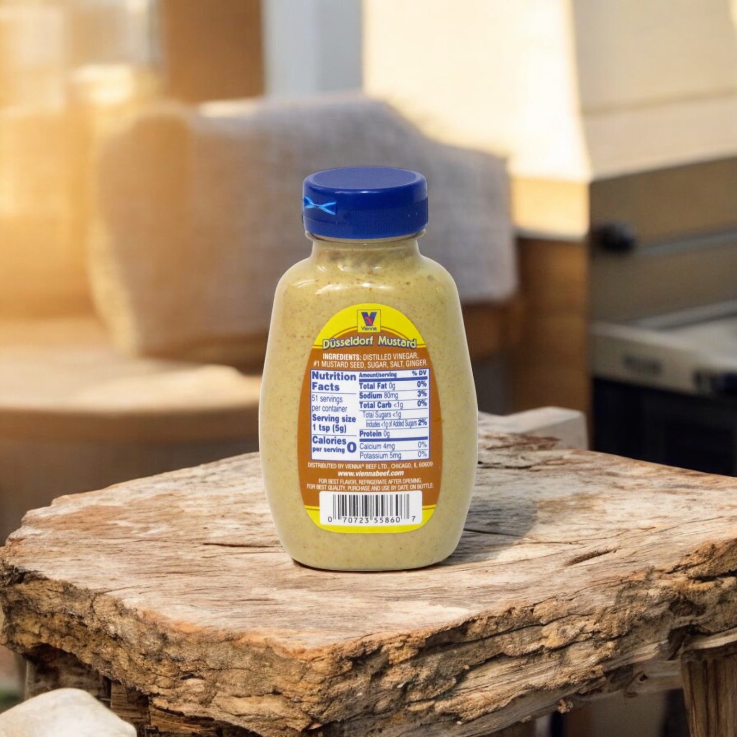 A 1-gallon jar of Easy Lunches Vienna Dusseldorf Mustard, a gluten-free German-style mustard, sits on a rough wooden surface outdoors in natural sunlight.