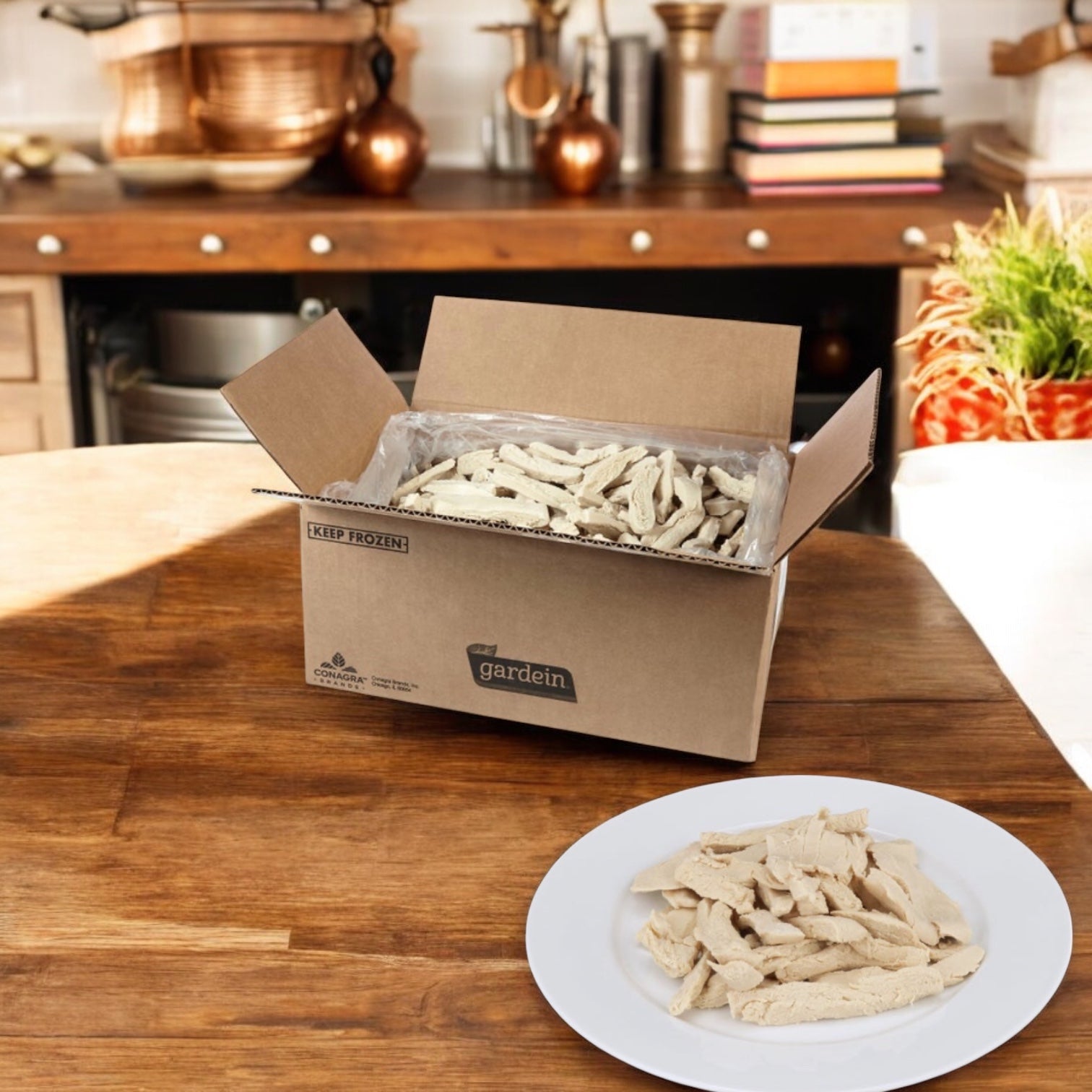 An open box of Easy Lunches Gardein Vegetarian Vegetable Chicken Strips sits on a kitchen table, with several plant-based strips served on a white plate in the foreground.